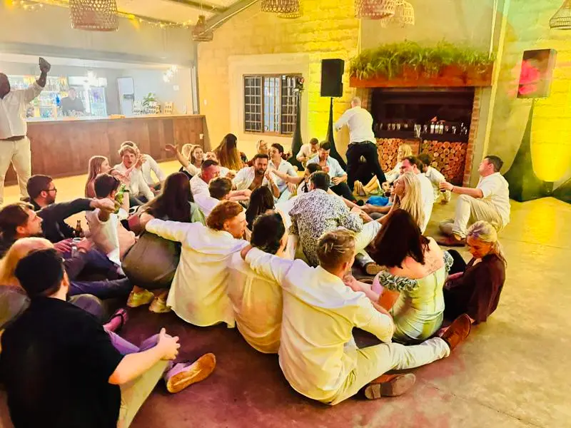 Guests sitting on the floor for a dance at Andrew and Pia's Haycroft Farm wedding