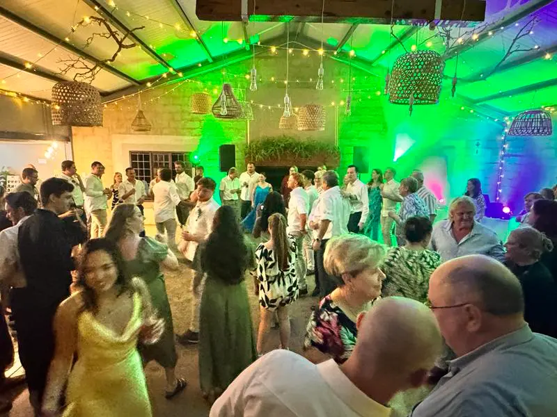Guests dancing under green and purple light at Andrew and Pia's wedding