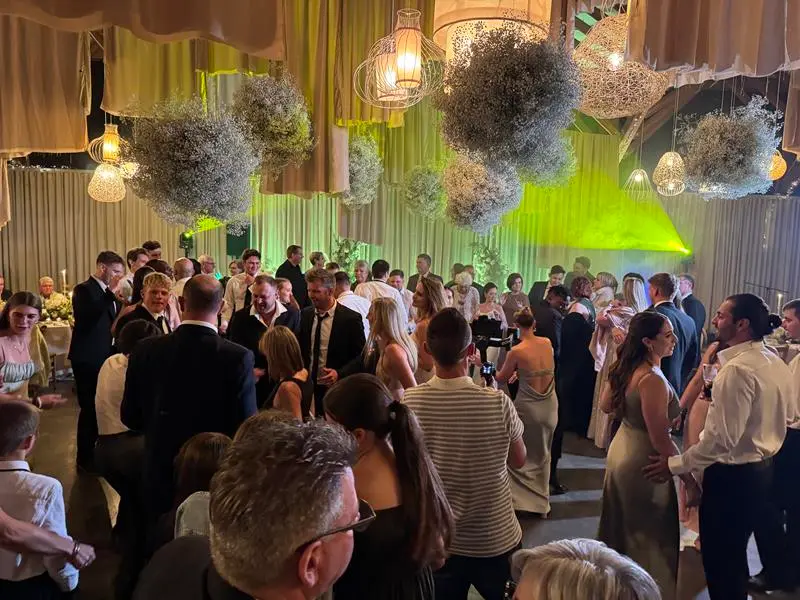 A busy wedding dancefloor under coloured lighting and hanging gypsophila