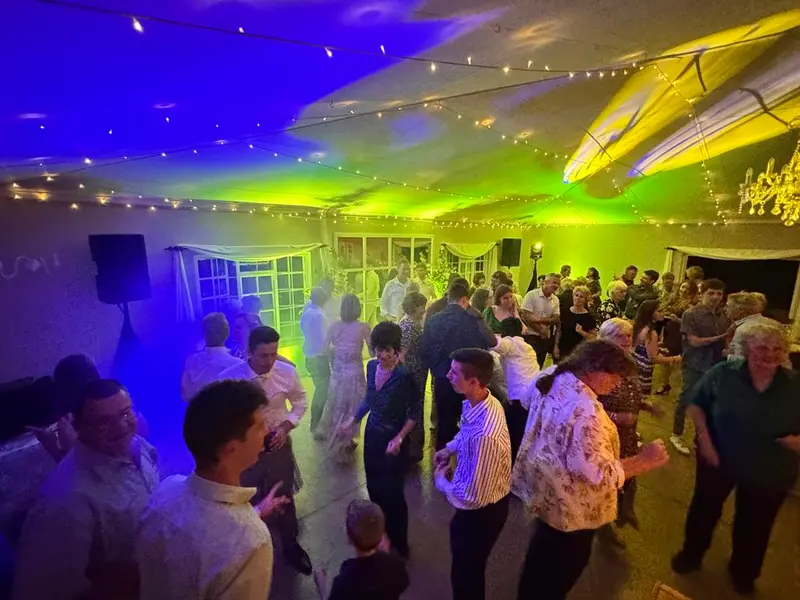 Guests dancing under green, purple and yellow light in a marquee