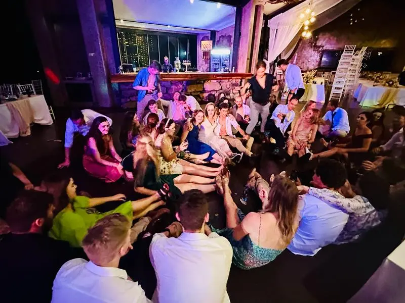 Guests sitting on the floor for a dance at a Netherwood Farm wedding