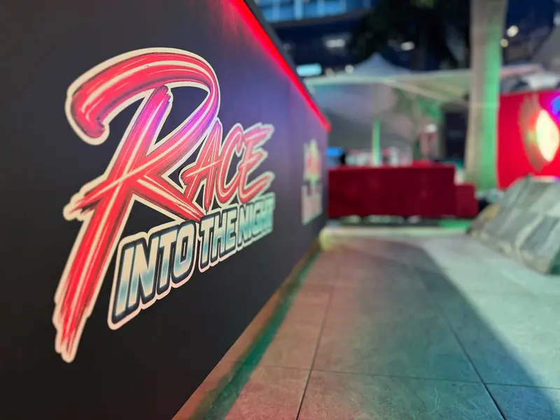 Neon Race Into The Night sign on a black wall at the SACSC After Party