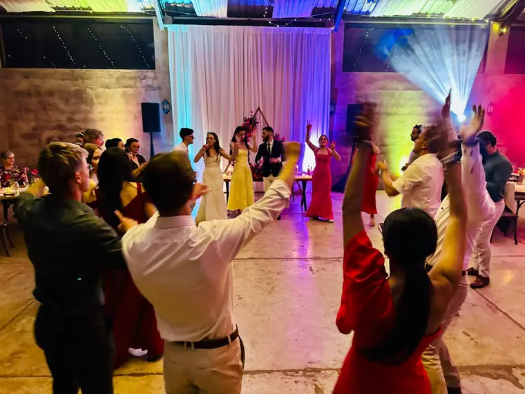 Guests dancing with hands in the air through lighting haze