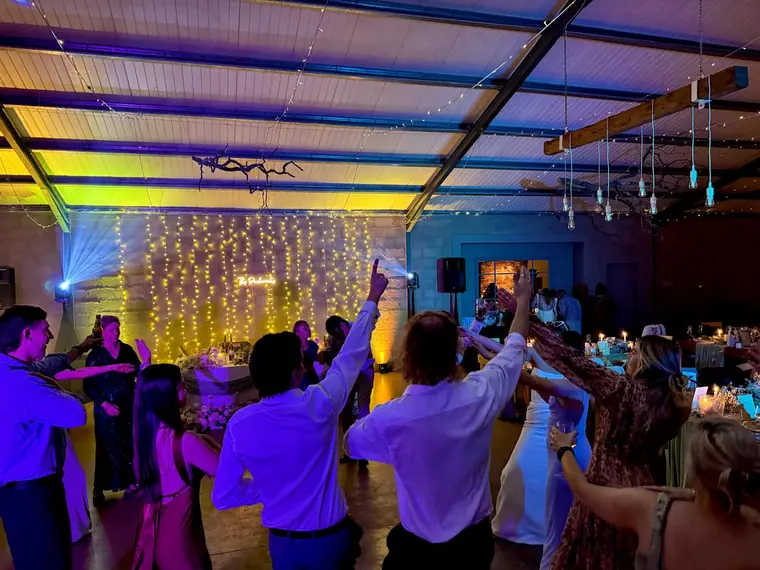Wedding guests with arms raised under blue dancefloor lighting