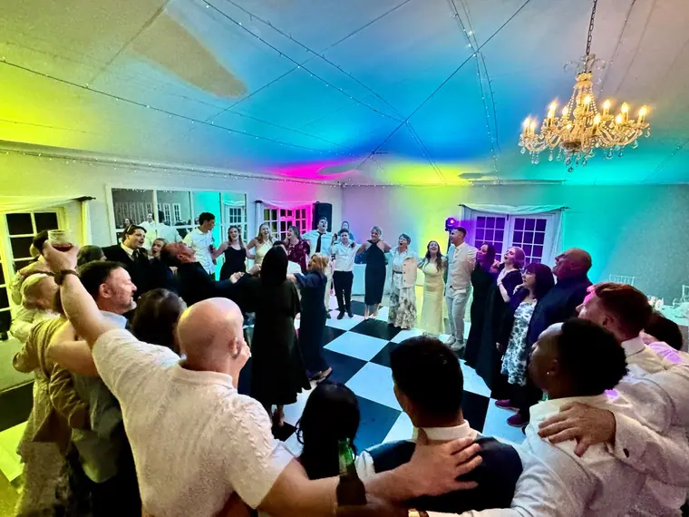 Wedding crowd on the dancefloor beneath a chandelier