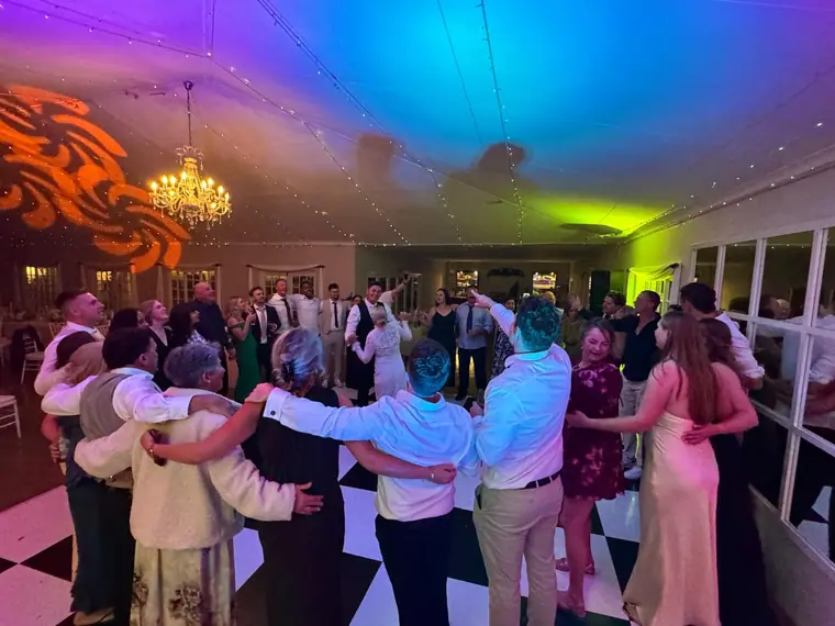 Guests dancing in a hall lit in orange and green