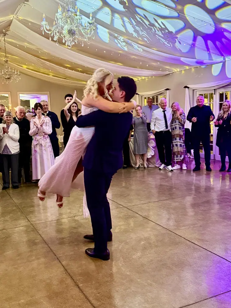 First dance surrounded by guests in a chandelier-lit hall