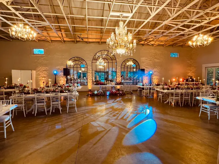 Wedding reception hall with chandeliers and blue uplighting before guests arrive