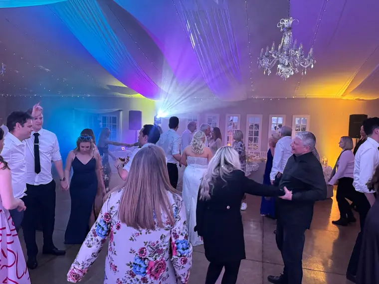 Guests dancing in a circle under purple and blue lighting