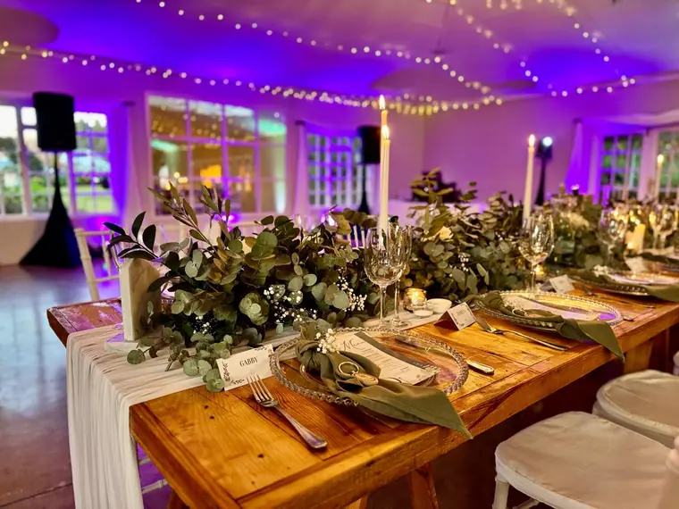 Banquet table dressed with greenery and candlelight