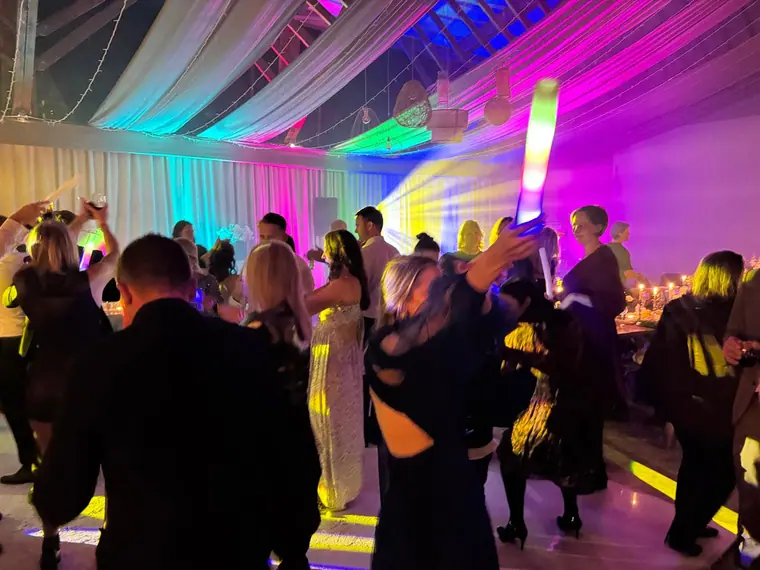Wedding crowd dancing beneath a draped ceiling with pink lighting