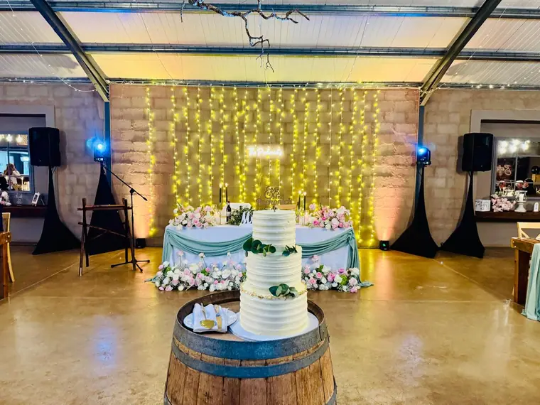 Wedding cake on a barrel against a fairy-light backdrop at Haycroft Farm